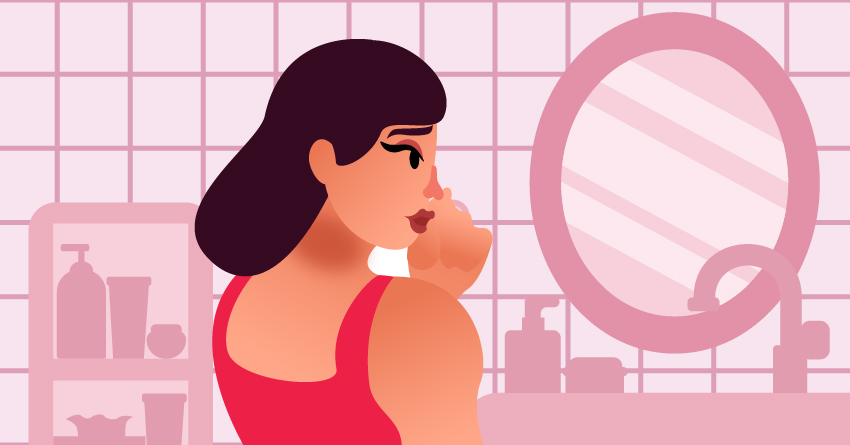 A woman looking into the mirror, worried about random dark spots in her skin. 