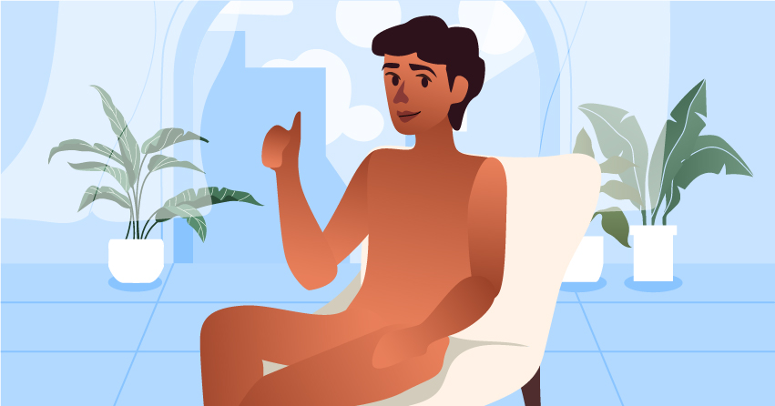 A naked man sitting in a couch and doing an "ok" hand sign. 