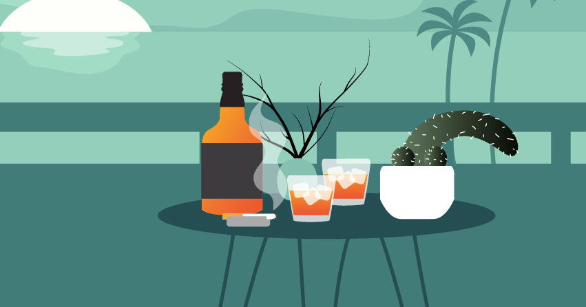 A table filled with a whiskey bottle, whiskey glasses, and a pot of cactus. 